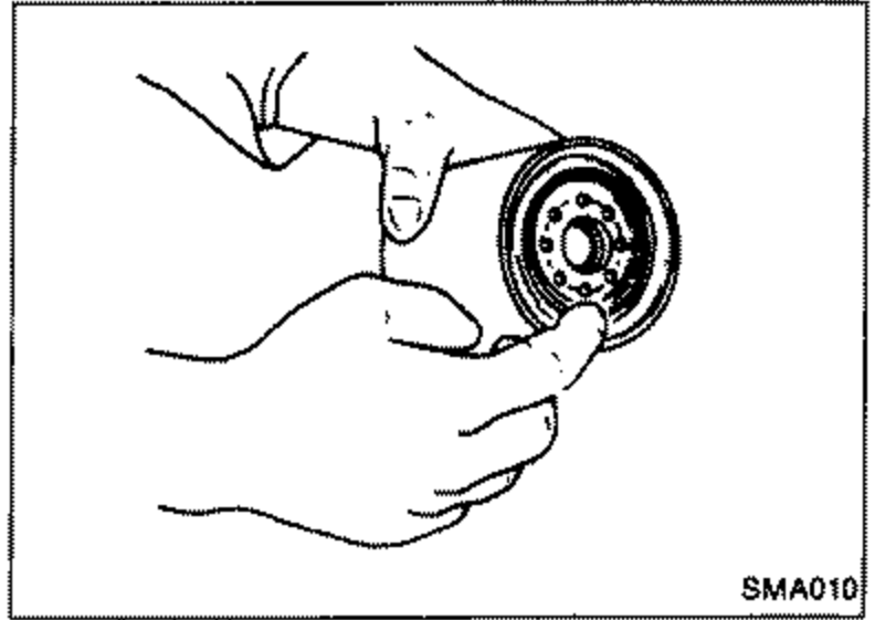 Illustration of a hand cleaning the oil filter mounting surface and handling the oil filter on the cylinder block.