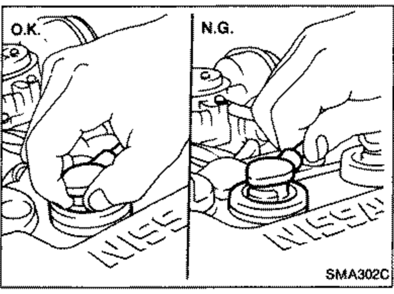 Two side-by-side hand illustrations labeled 'O.K.' (left) and 'N.G.' (right) showing the correct and incorrect way to disconnect ignition wires from spark plugs at the boot, near the NISSAN-marked rocker cover.