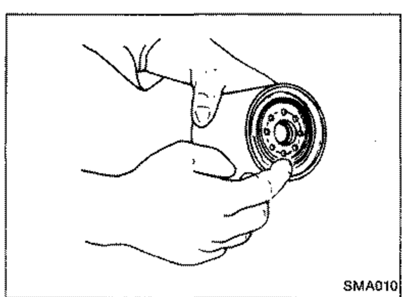 Illustration of hands installing a new oil filter onto the cylinder block, smearing engine oil on the rubber seal.