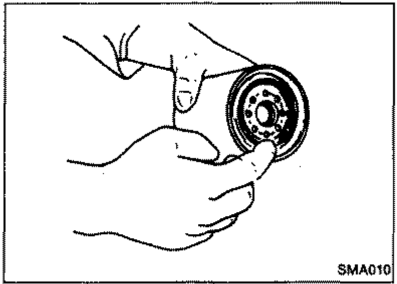 Line drawing of a hand applying a little engine oil to the rubber seal of the new oil filter before installation.