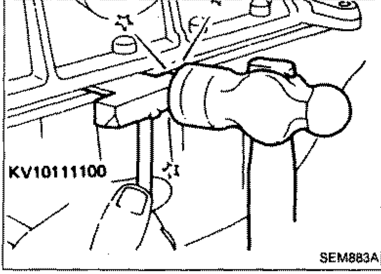 Tool KV10111100 inserted between cylinder block and oil pan to separate them. Hand holding the tool against the mating face.