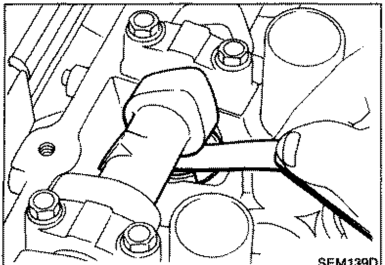 A feeler gauge being inserted between the valve lifter and camshaft to measure clearance.
