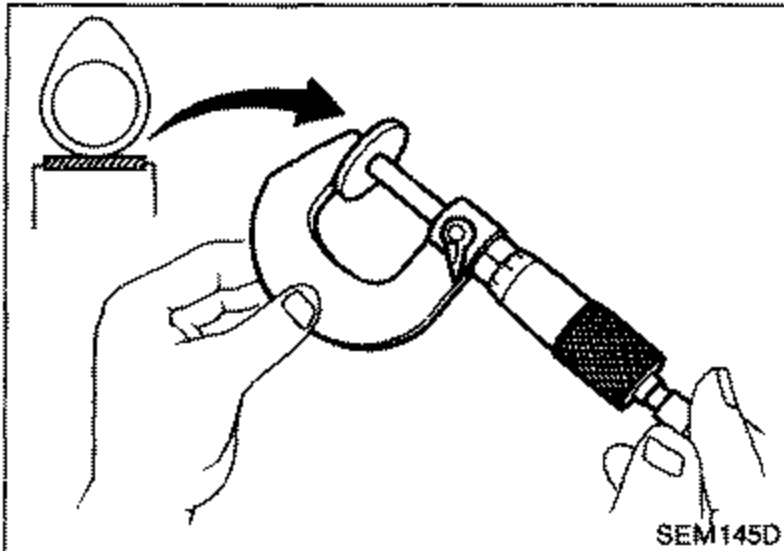 A micrometer being used by hand to measure thickness of the removed adjusting shim.