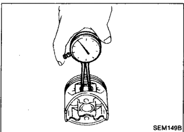 A dial gauge / inside micrometer being used to measure the inner diameter of the piston pin hole 'dp' on a piston held by hand.