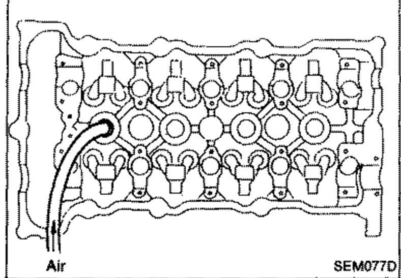 Cylinder head with an air hose adapter installed in a spark plug hole. Label 'Air' with arrow indicating air pressure being applied to hold valves in place.