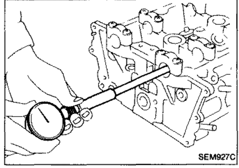 Illustration showing a dial bore gauge measuring the inner diameter of the camshaft bearing in the cylinder head, with camshaft bracket installed.
