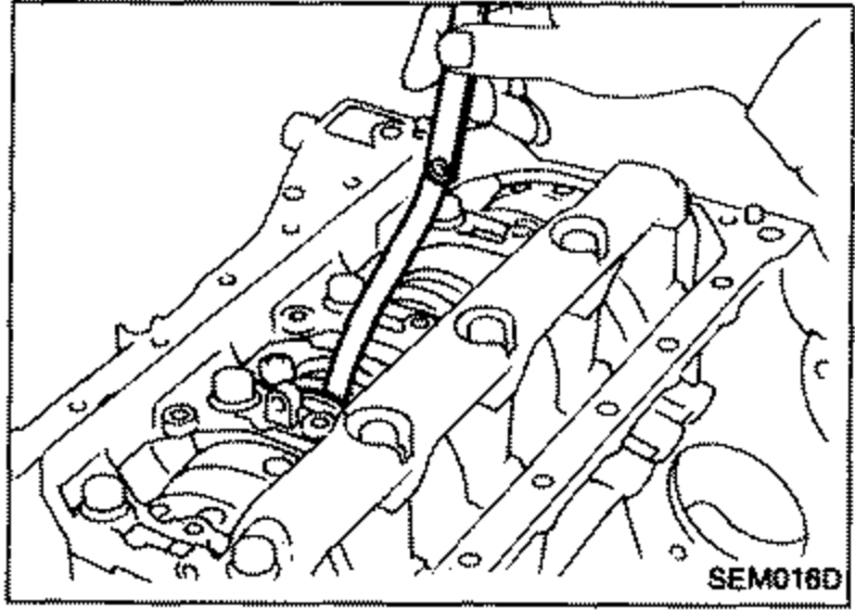 Measuring connecting rod side clearance with a feeler gauge inserted between the connecting rod and crankshaft journal.