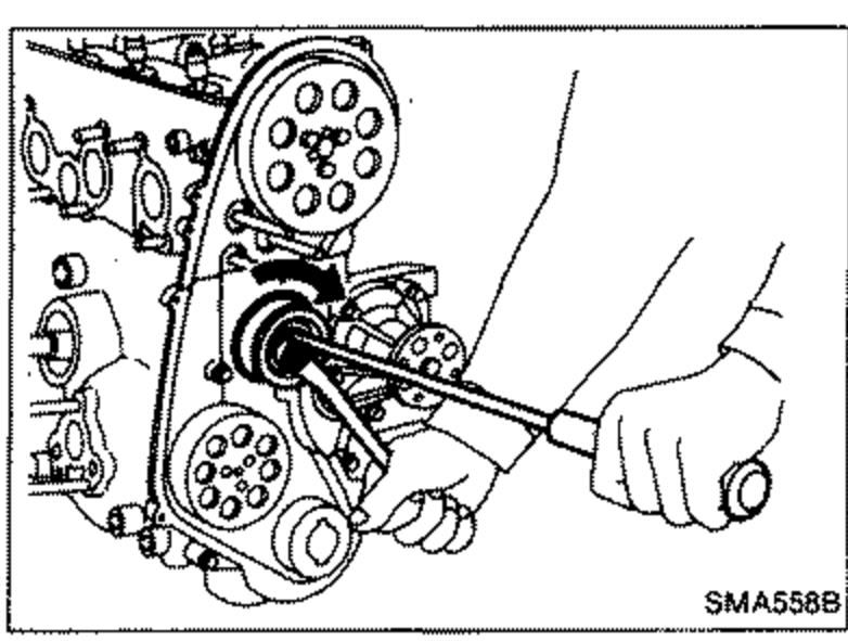 Hand using a tool/wrench to rotate the tensioner on the front of the engine, with the timing belt and sprockets visible.