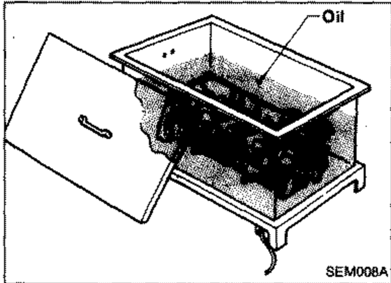 Cylinder head being heated in an oil bath/tank to 150 to 160°C to remove the valve guide. Labeled 'Oil'.