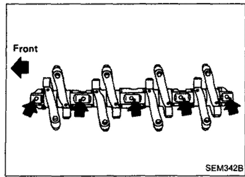 Rocker shaft assembly with rocker arms, front direction indicated by an arrow on the left.