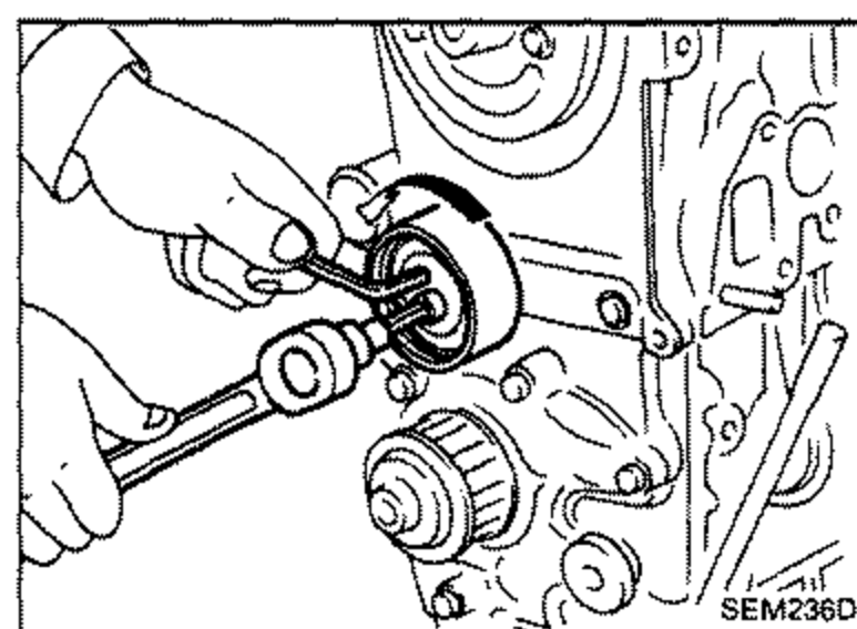 Illustration of a hand using a tool to install the timing belt tensioner and return spring on the engine. Shows the tensioner pulley area.