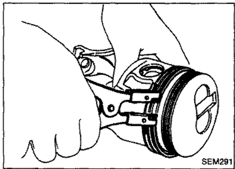 Hand removing piston rings from a piston using a piston ring tool.