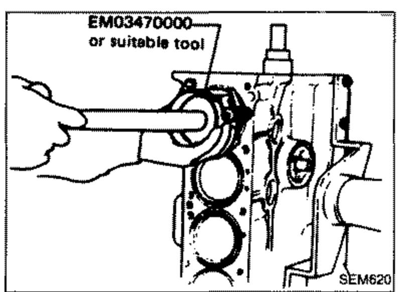 Piston being installed into a cylinder bore using tool EM03470000 or suitable tool (a piston ring compressor/installer). Shows the cylinder block with the tool guiding the piston into the bore.