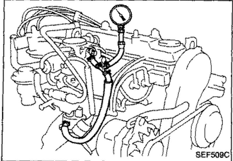 Engine compartment view showing the fuel pump fitted in place with a pressure gauge connected via hoses for the fuel pressure test.
