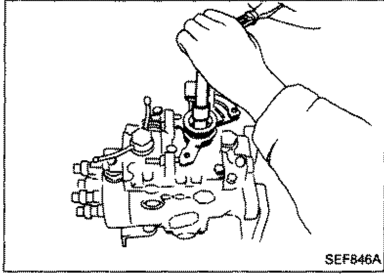 Hand using a tool to remove the nut, spring washer, spring seat and spring from the control lever on top of the pump.