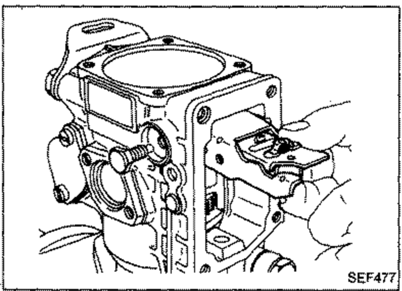Governor lever assembly being removed from the pump body, with a hand holding the assembly.
