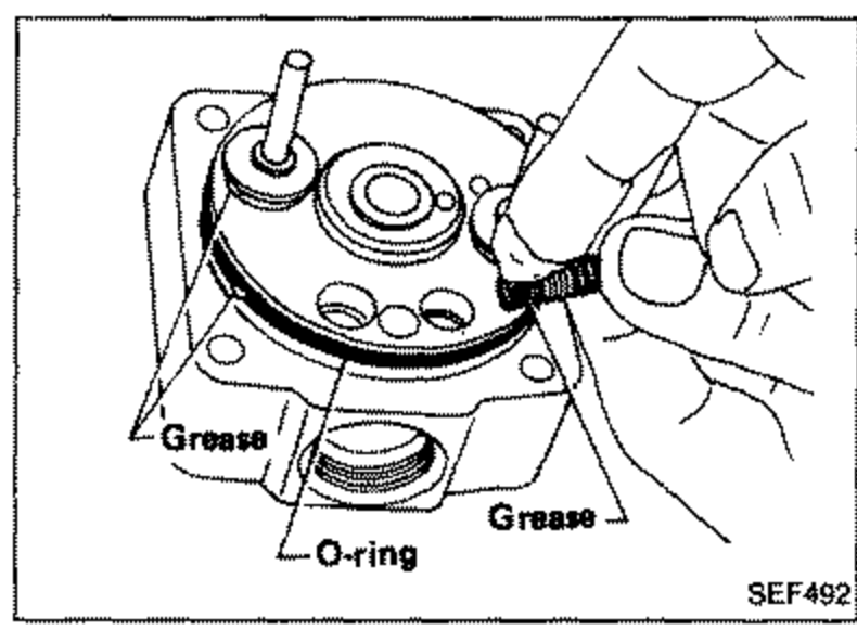 Distributor head with grease applied to guide pin, shim and spring seat. Labels: Grease, O-ring, Grease.