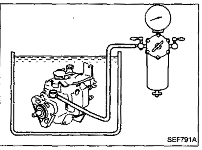 Injection pump with overflow connector being replaced by a bolt for the air tightness test; a hand/tool works at the top of the pump.