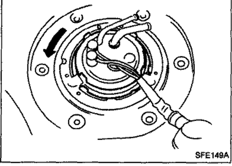 View of the lock ring being rotated (arrow) for removal, exposing the fuel gauge unit beneath.