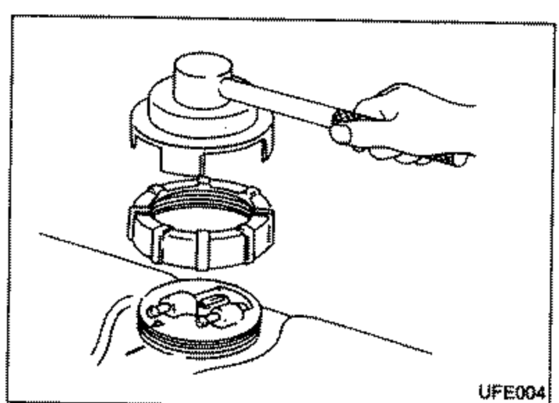 View of the fuel gauge/pump unit with the lock nut being removed using the special service tool KV999G0010 (lock ring socket on a handle), and the upper plate exposed.